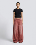 Women's low rise baggy jeans in faded red on model — wide leg pooling over shoes